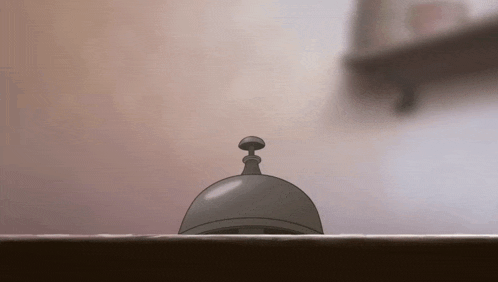 a bell is sitting on a table with a shelf in the background .