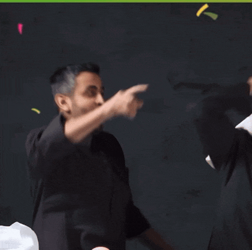 a man in a black shirt is dancing in front of a black background