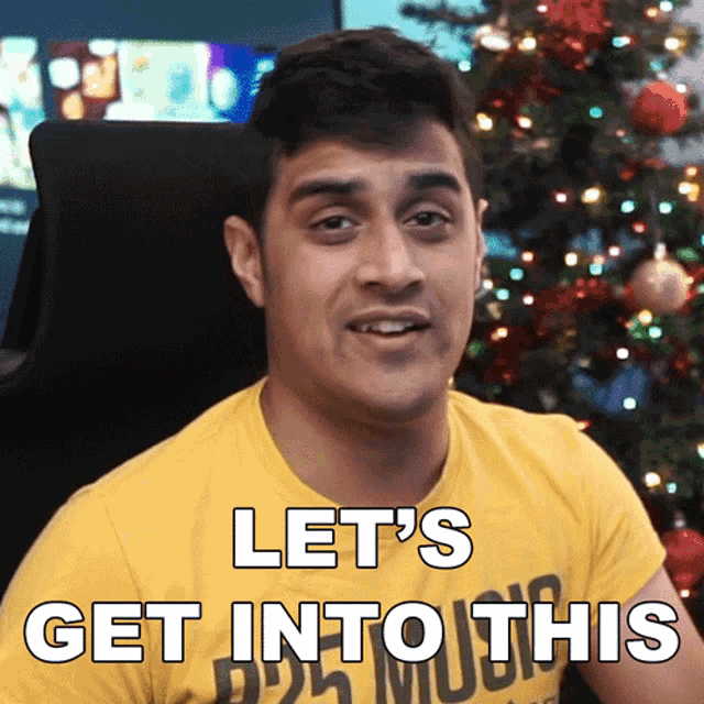 a man in a yellow shirt says let 's get into this in front of a christmas tree