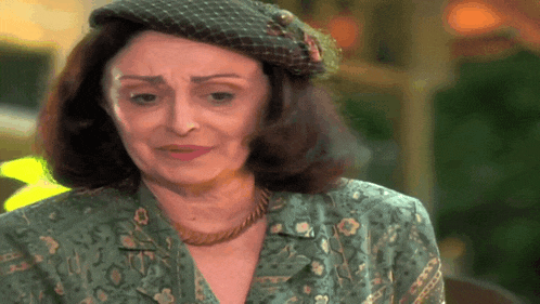 a woman wearing a hat and a necklace is looking at the camera