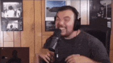 a man wearing headphones is laughing into a microphone .