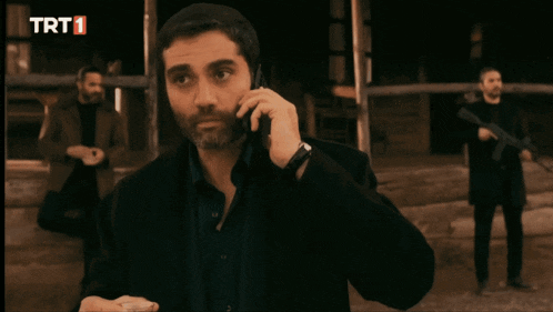 a man holds a cell phone in front of a trt logo