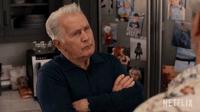 an older man with his arms crossed stands in front of a refrigerator with pictures on it and says netflix on the bottom