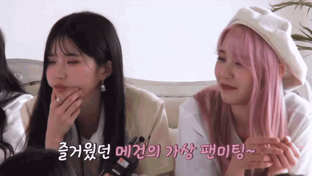 two girls with pink hair are sitting next to each other on a couch and one of them is wearing a white beret
