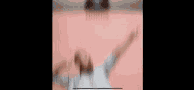 a blurry picture of a person holding a basketball in front of a pink wall .