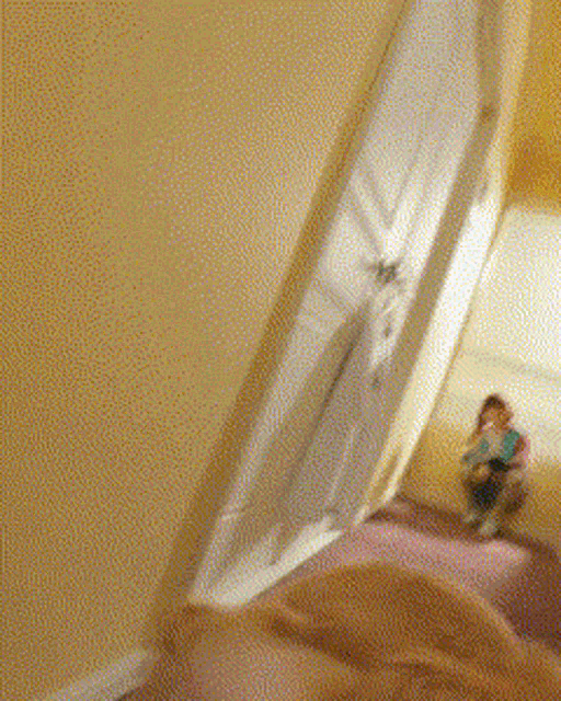 a person is holding a clock in front of a blurred image of a child sitting on a bed