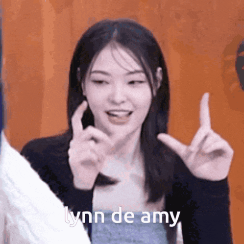 a woman is making a gesture with her hands and says lynn de amy in the corner .