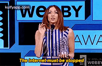 a woman is standing in front of a microphone at a awards ceremony and saying the internet must be stopped .