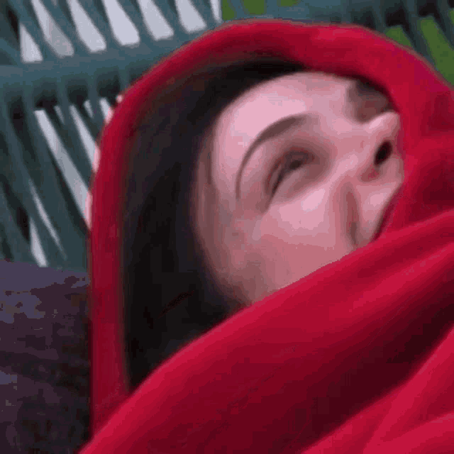 a woman is wrapped in a red blanket and smiling