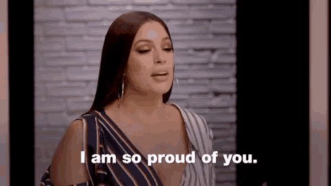 a woman is saying `` i am so proud of you '' in front of a brick wall .