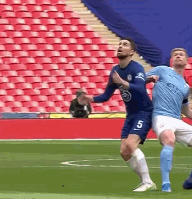 a soccer player with the number 5 on his shirt is being tackled by another player