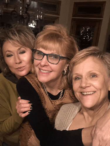 three women are posing for a picture and one of them has glasses on