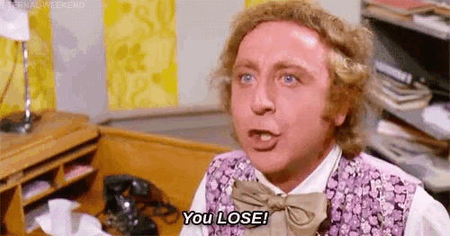 a man in a purple vest and bow tie is saying `` you lose '' while sitting in front of a desk .