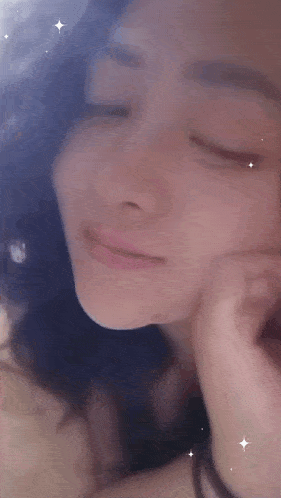 a close up of a woman 's face with a hand on her chin