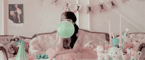 a woman is sitting on a couch wearing a party hat and a birthday hat .
