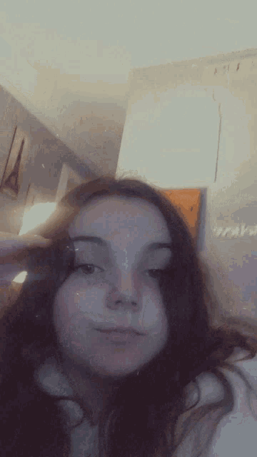 a girl with long hair is taking a selfie in a bedroom .