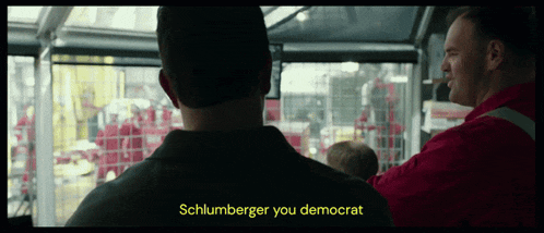 a man in a red shirt is talking to another man in a black shirt who says schlumberger you democrat
