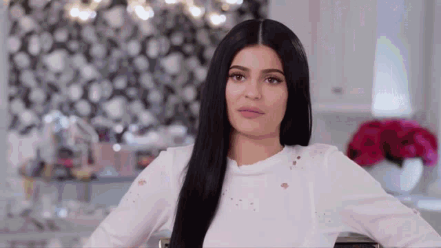 a woman with long black hair is wearing a white sweater .