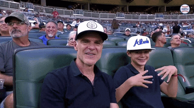 a boy wearing an atlanta hat sits next to his father