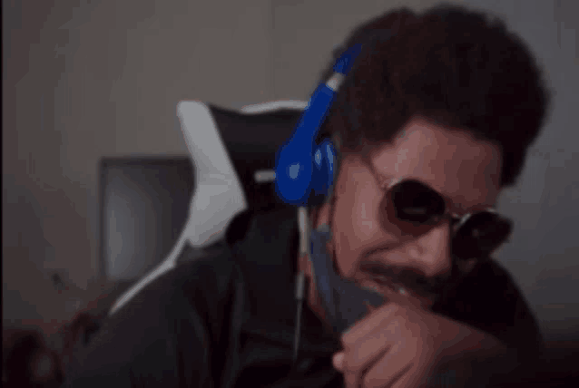 a man wearing headphones and sunglasses is sitting in front of a computer
