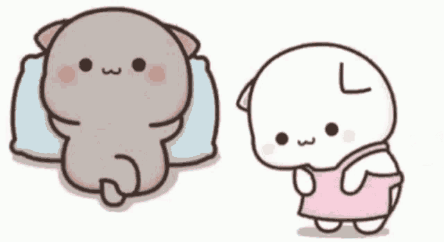 a cat is laying on a pillow and a cat is standing next to each other .