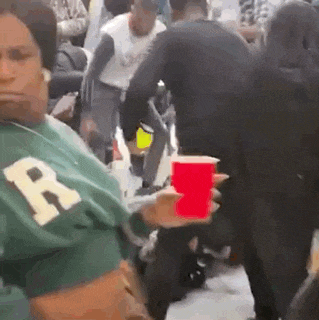a woman is holding a red cup in front of a crowd of people .