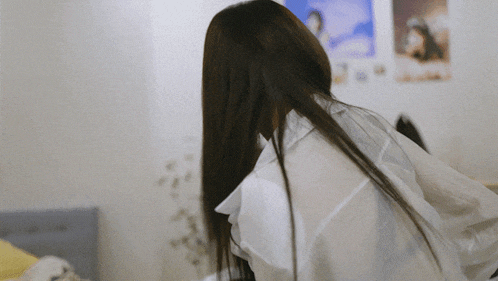a woman with long hair wearing a white shirt is looking over her shoulder