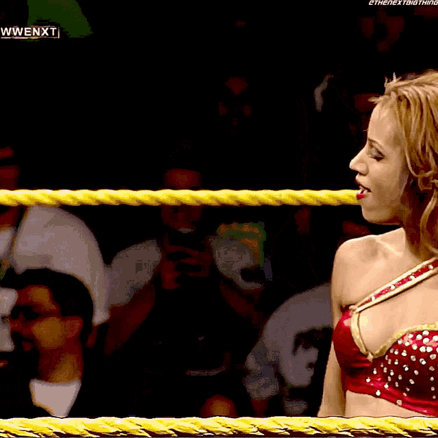 a woman in a red top is in a wrestling ring with the words wwe nxt on the bottom