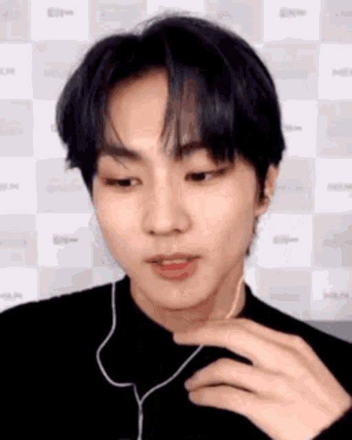 a young man wearing headphones and a black shirt is looking at the camera .