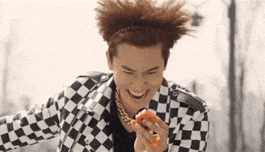 a man wearing a headband and a checkered jacket is smiling and eating a donut