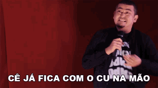 a man singing into a microphone with the words " ce ja fica com o cu na mao " above him