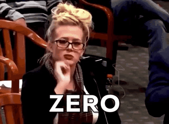 a woman wearing glasses and a scarf is sitting in a chair with the word zero above her