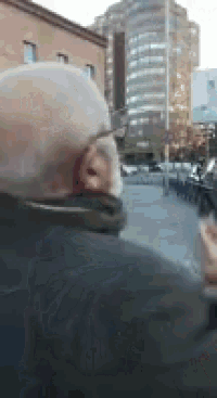 a man with glasses and a beard is walking down the street .
