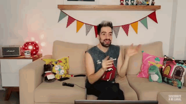 a man sitting on a couch with a rolling stones shirt on