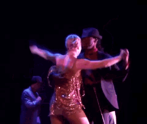 a man and two women are dancing on a stage in a dark room
