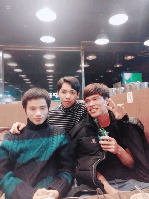 a man in a black jacket with the letter s on it poses with two other men
