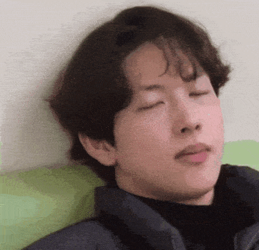 a young man is laying on a couch with his eyes closed and making a funny face .