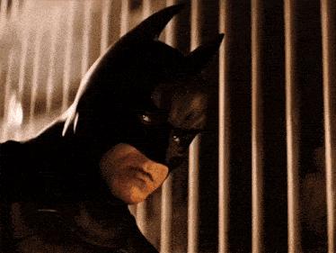 a man in a batman costume stands in front of a fence