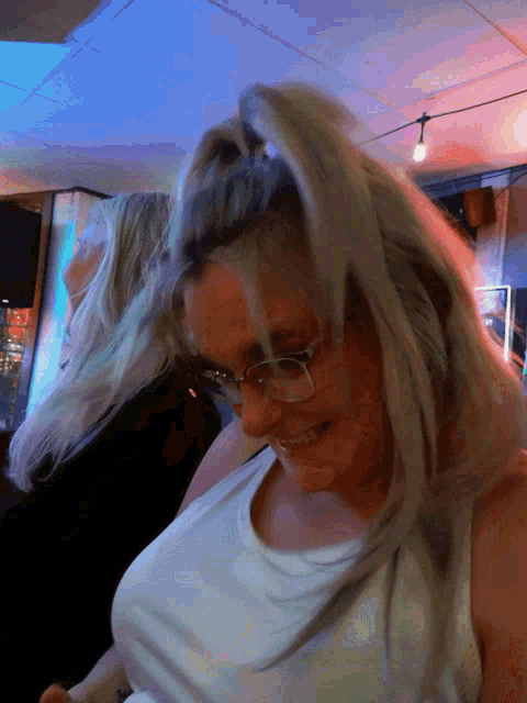 a woman with blonde hair and glasses is smiling