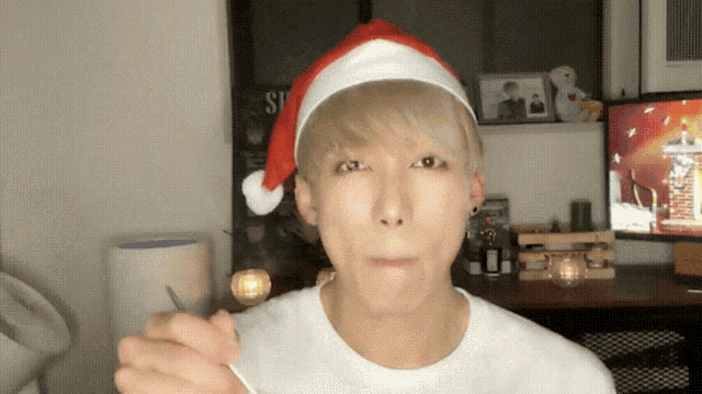 a man wearing a santa hat is holding a spoon in his hand