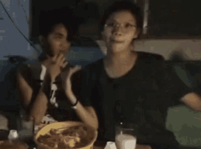 two people are sitting at a table with a bowl of food .