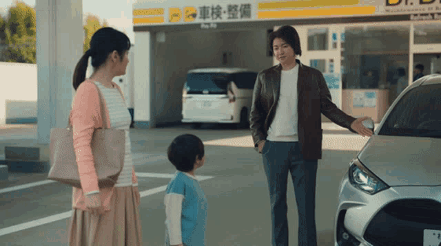 a man and woman are standing next to a car in front of a sign that says ' maintenance ' on it