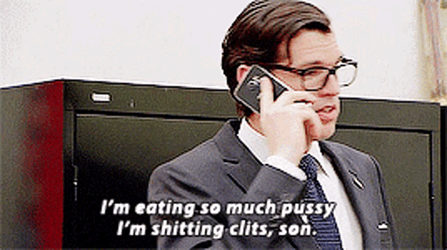 a man in a suit and tie is talking on a cell phone and says " i 'm eating so much pussy "