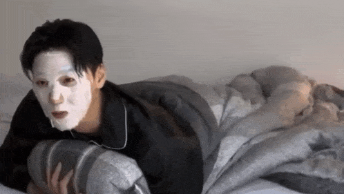 a man wearing a white mask is laying on a bed .