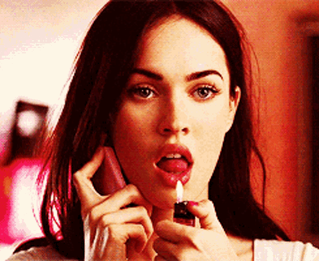 a woman is talking on a cell phone while holding a lighter to her face