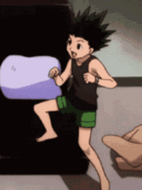a boy in a black tank top and green shorts is jumping in the air