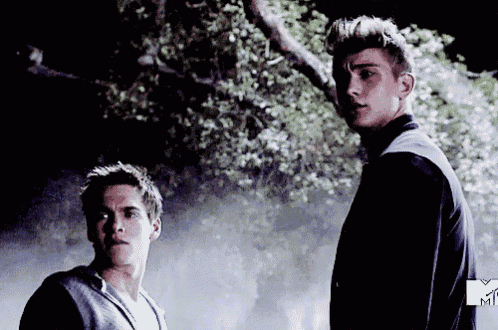two young men are standing next to each other in front of trees and a mtv logo