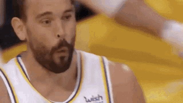 a basketball player with a beard is making a funny face while wearing a wish jersey .