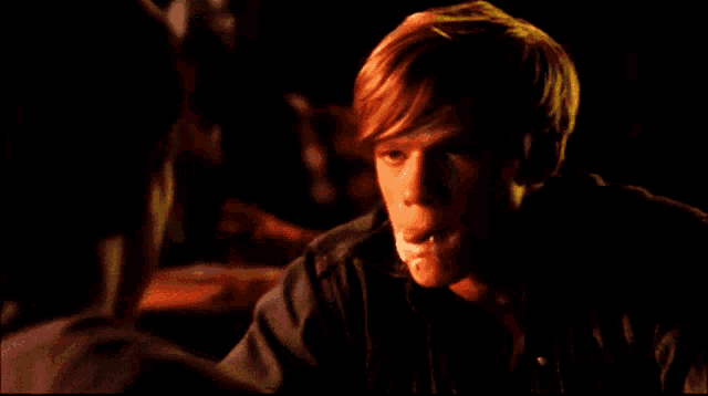 a young man with his tongue sticking out looks at another man