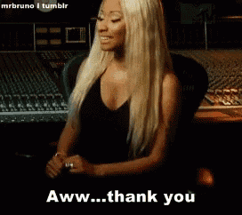a blonde woman in a black top is smiling and says aww thank you